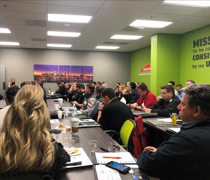 group of people sitting in a SERVPRO themed room for a meeting